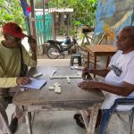 Dos adultos mayores, Antonio Taylor y Edgar Campbell, juegan juntos un juego de mesa,